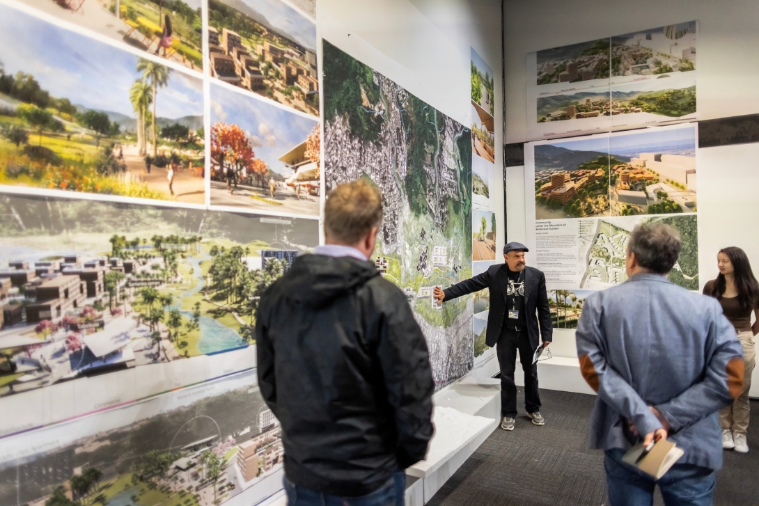 Man gestures in front of wall covered with maps