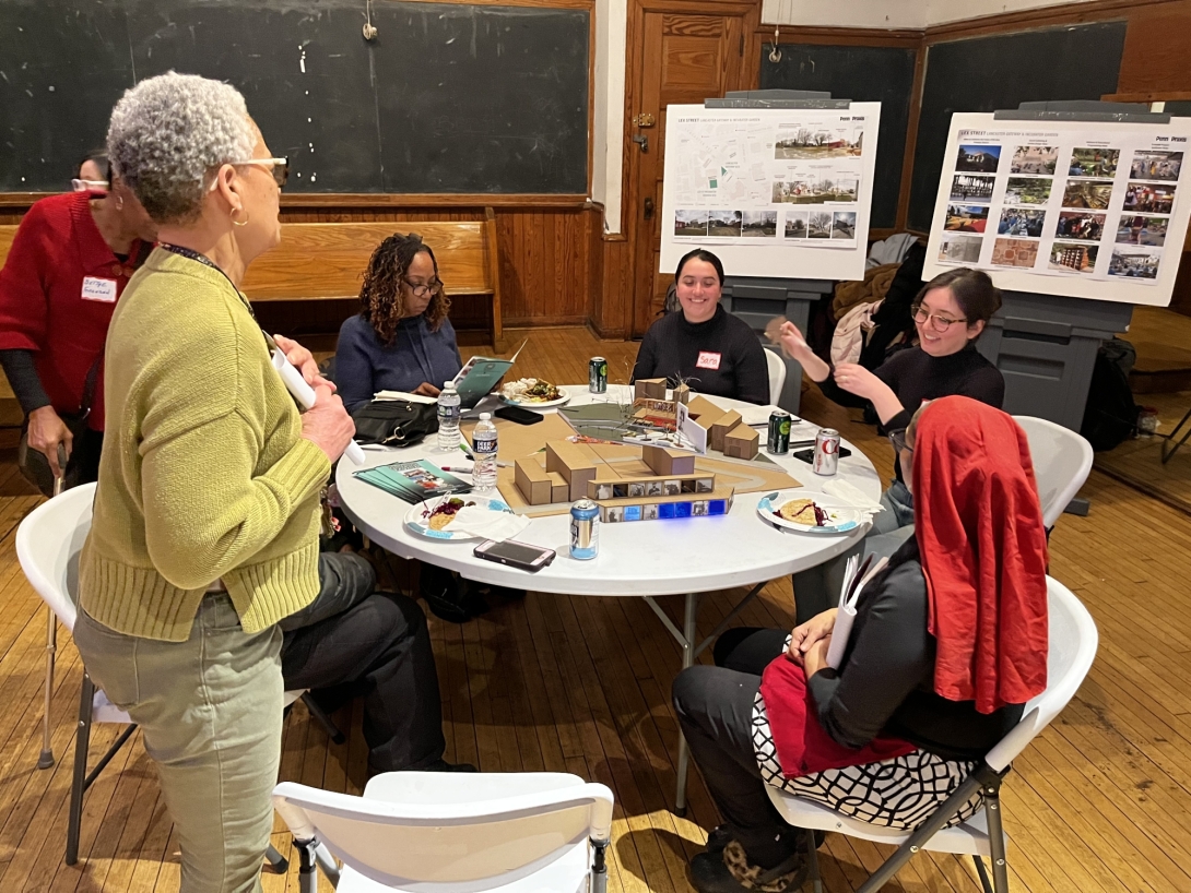 A group of women of different ages seated at a table with architectural models