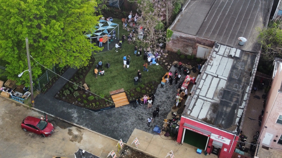 Drone photo of garden anchored by large tree at left and bounded by gym on right