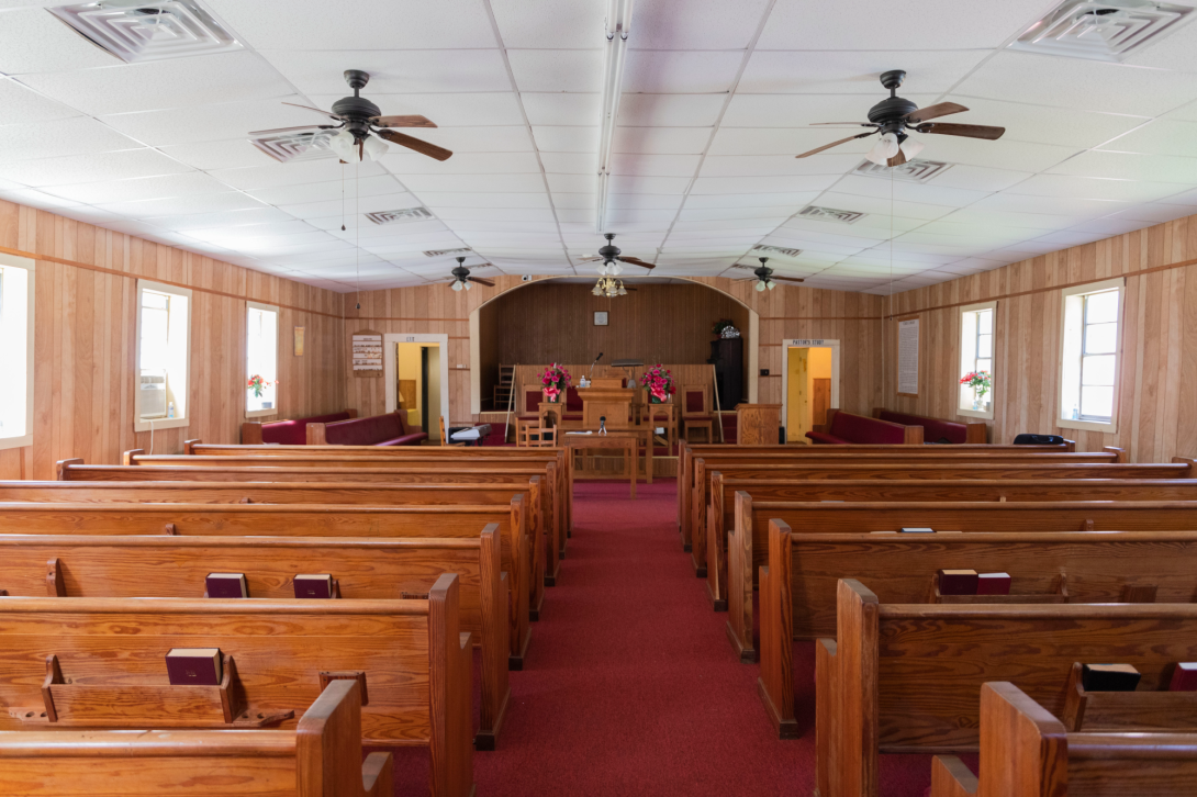 Interior of American rural church showing rows of wooden pews from behind