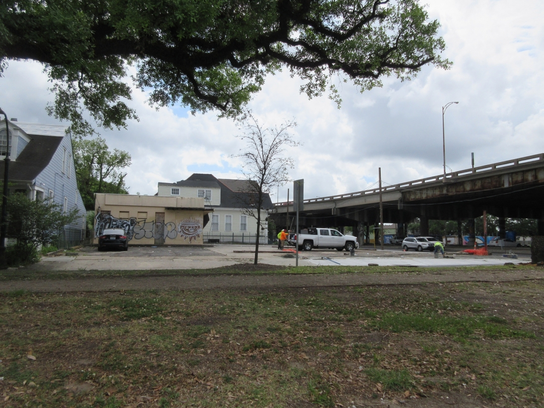 Photo of highway overpass next to empty lot and two low-rise houses