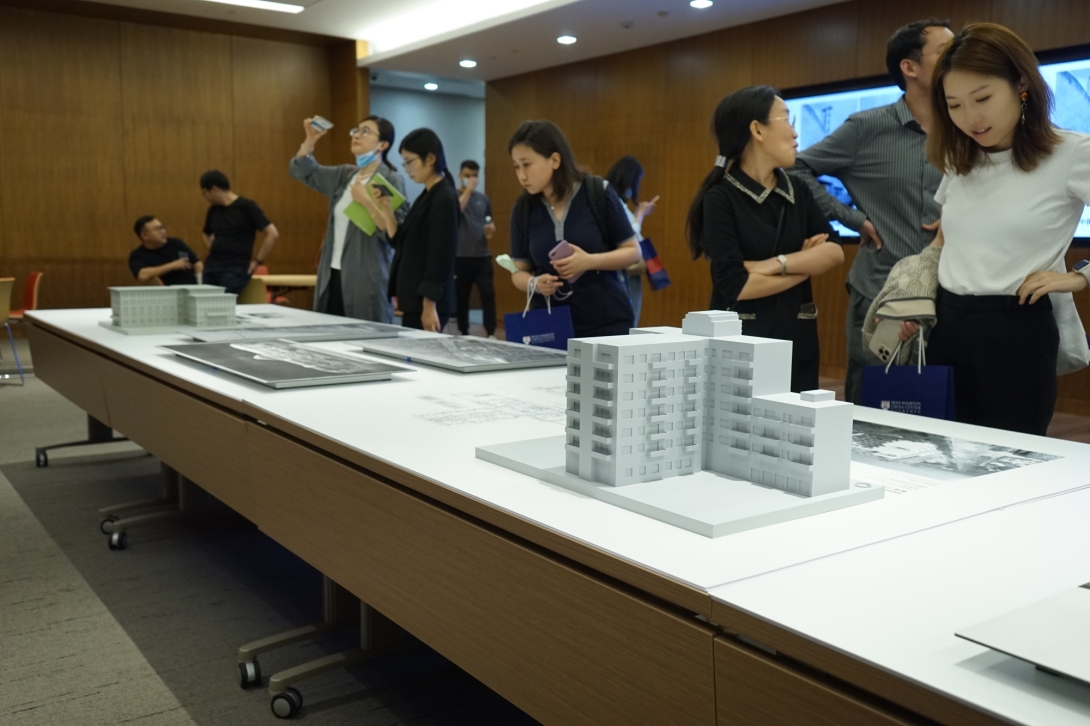 Group of people standing over table with architectural models