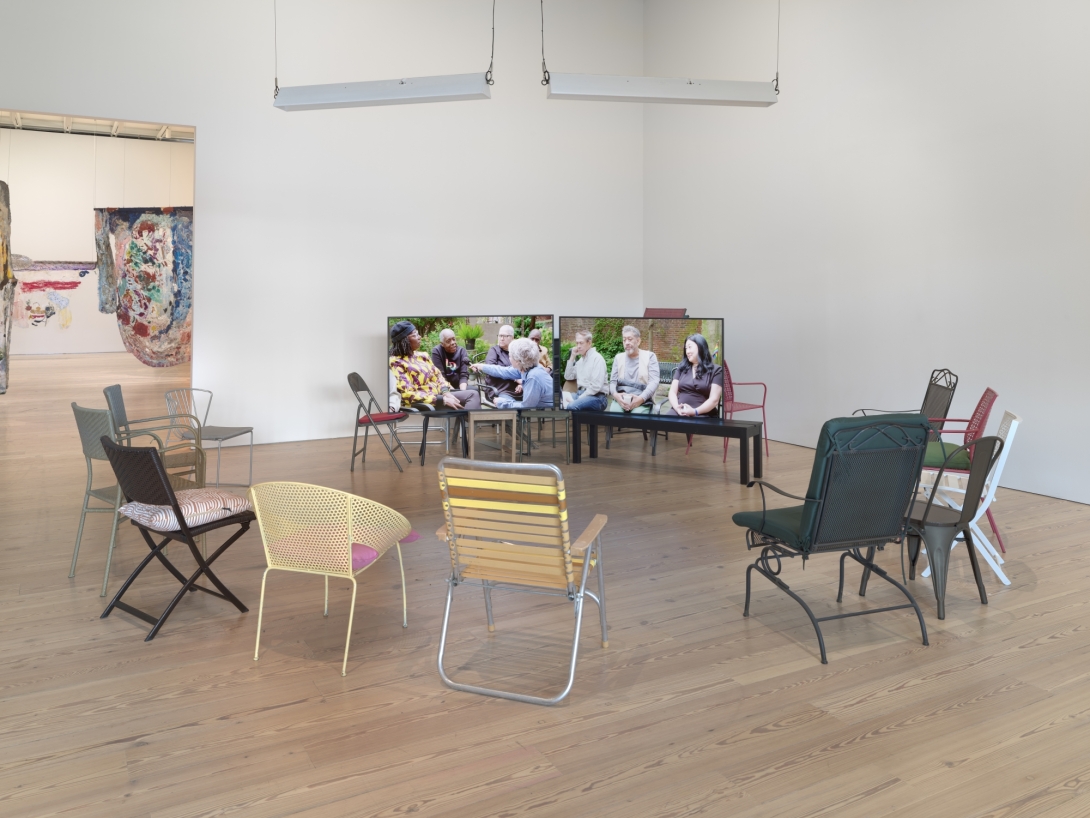 Folding chairs in front of monitors in gallery space