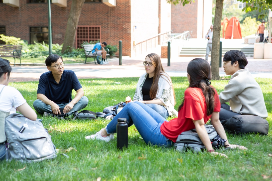 Group of young people seated on lawn outdoors in circle