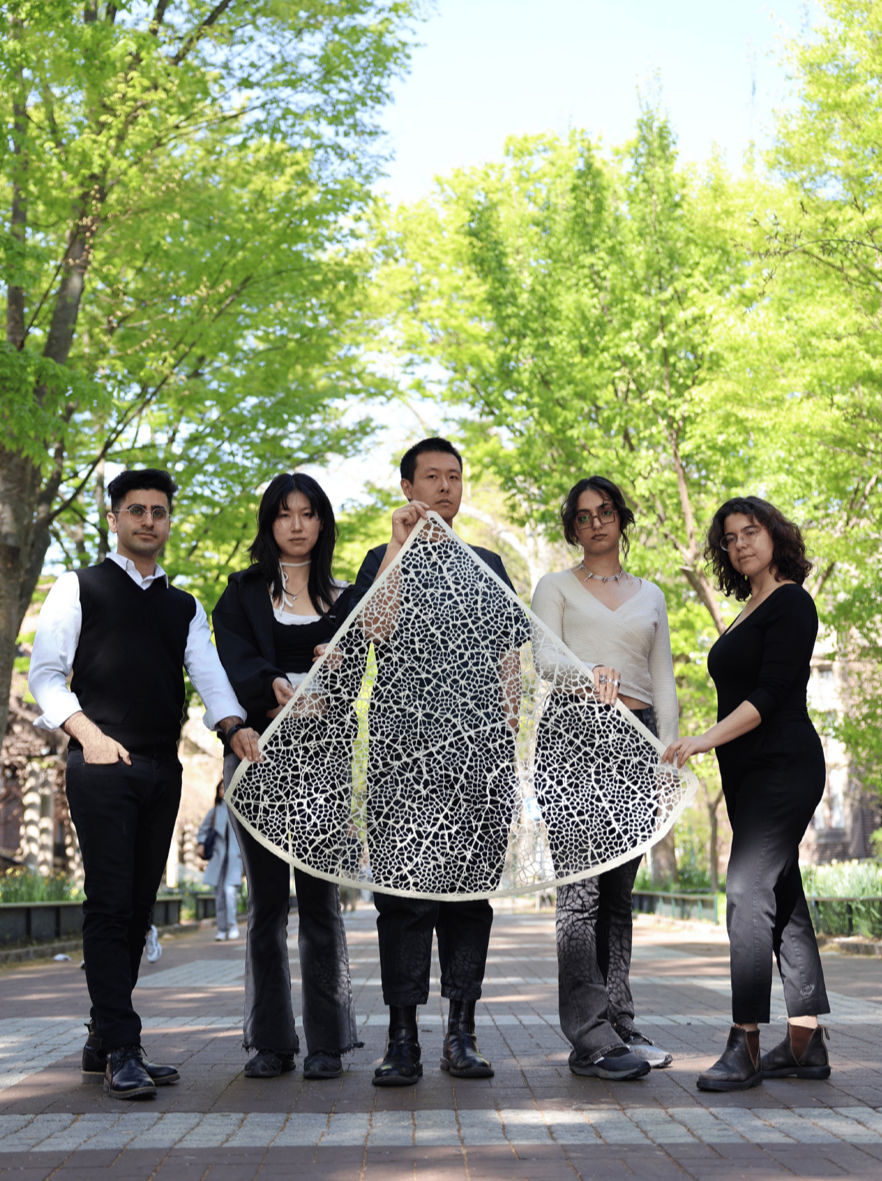 Four people hold up lattice wing-like structure