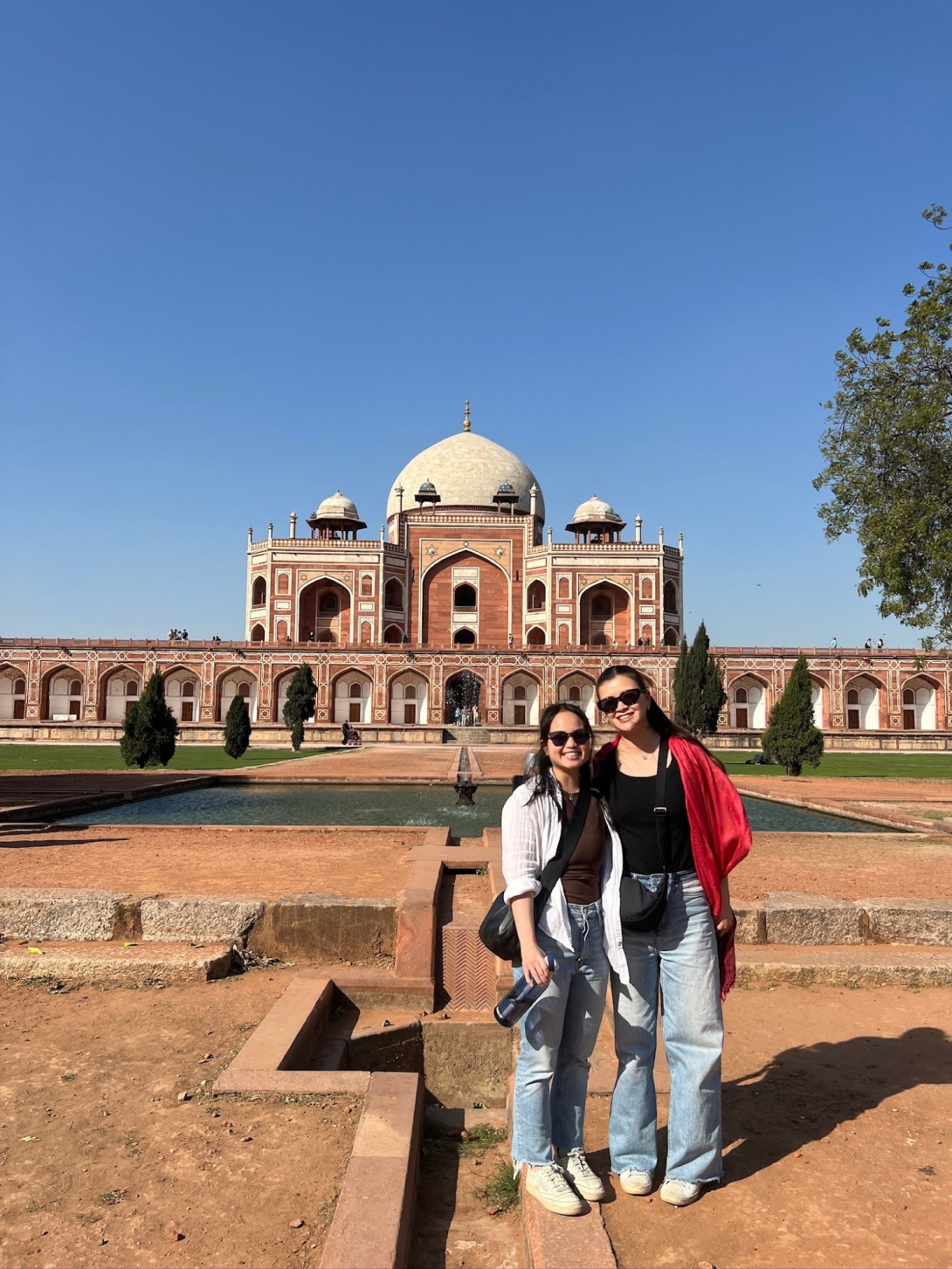 Two young women pose for photo in front of Indian temple