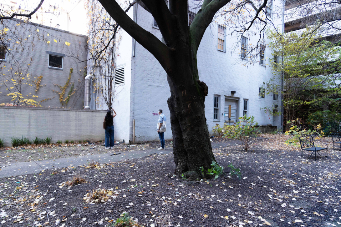 Two people survey a brick building in courtyard