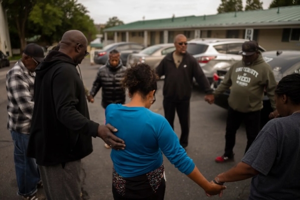 Members of the Lincoln Heights community praying together in a parking lot