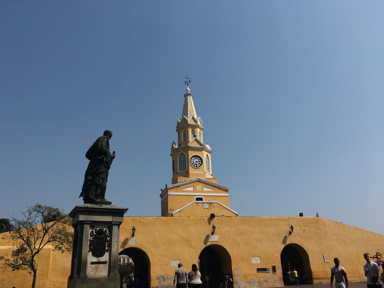 A stone tower with a clock and a statue of a man