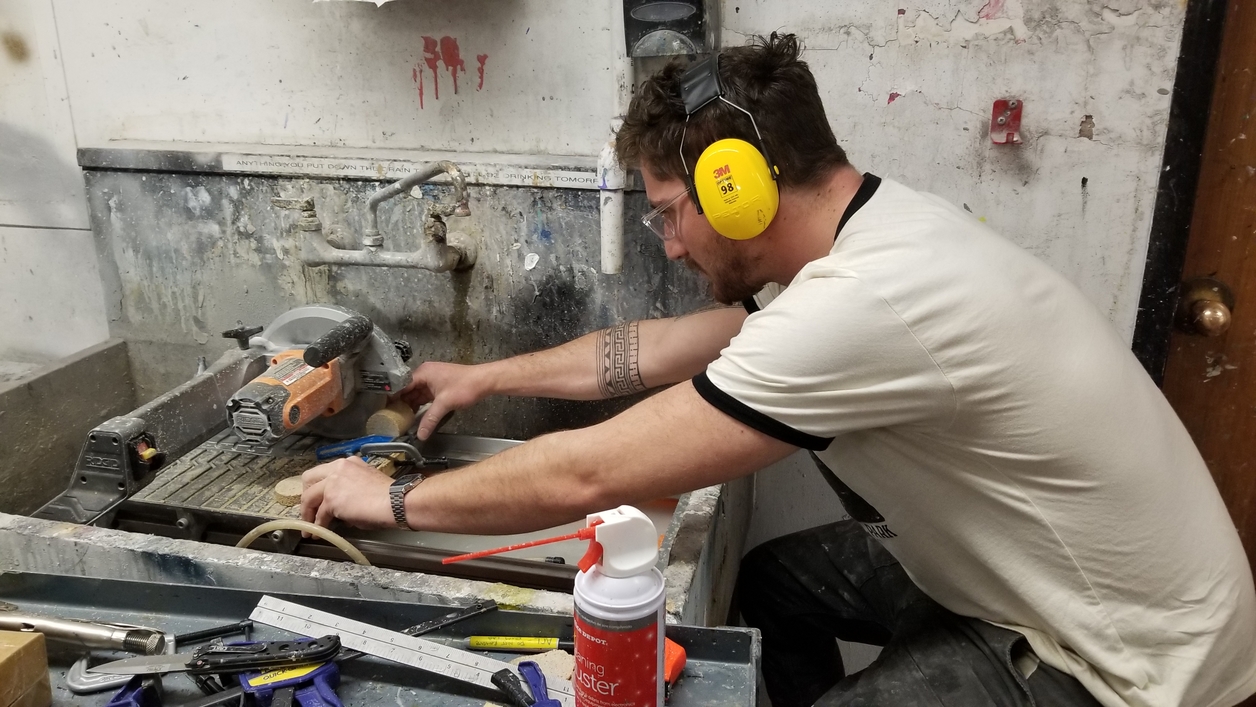 A man wearing headphones cuts cement using a large machine